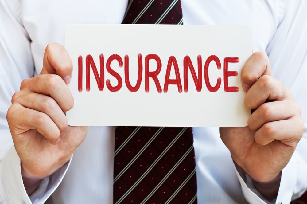 A Person Holding paper on which insurance is written