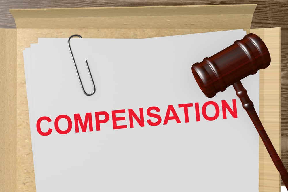 Compensation written on legal paper along with Judge hammer