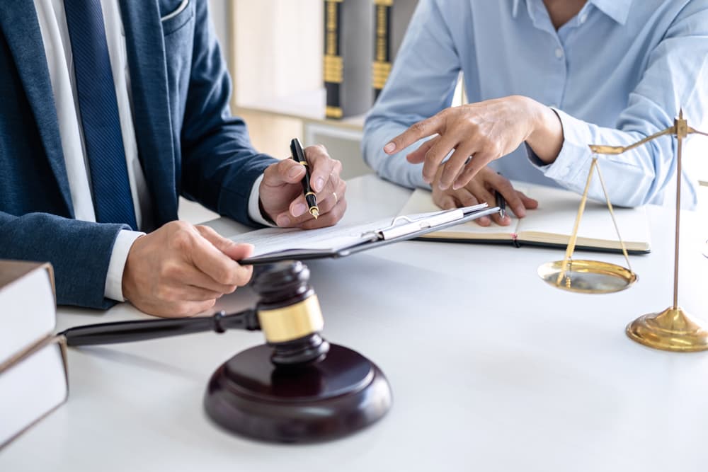 A client and a male lawyer or judge are engaged in a consultation during a team meeting at a law firm office, highlighting legal services and teamwork.