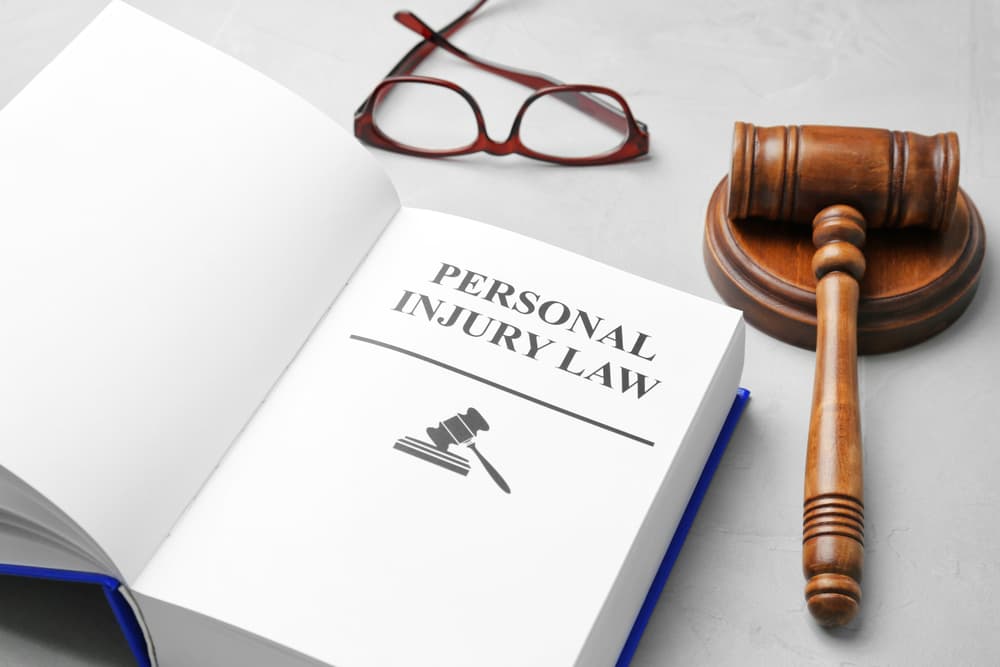 Book titled "PERSONAL INJURY LAW" with a gavel and glasses on a grey background.






