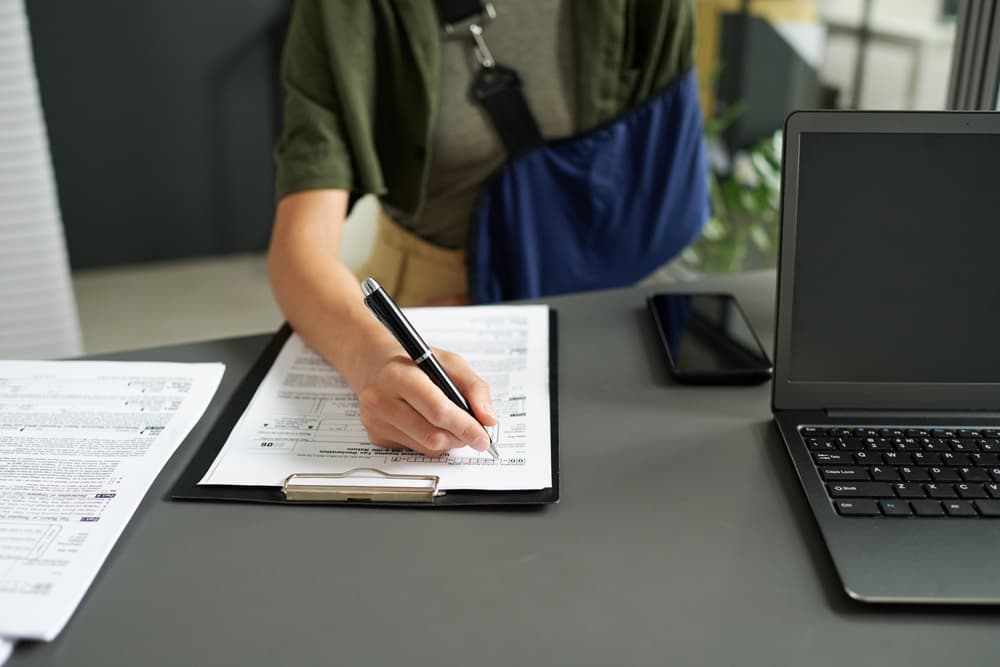 Woman with an injury completing and submitting paperwork.